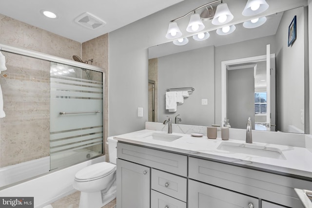 bathroom with double vanity, visible vents, bath / shower combo with glass door, and a sink