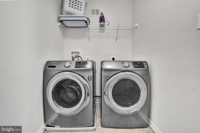 laundry area featuring laundry area, baseboards, visible vents, and washer and clothes dryer