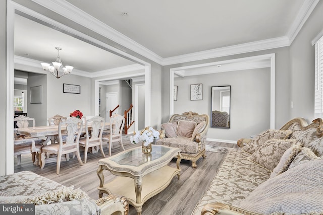 living area with a notable chandelier, stairs, crown molding, and wood finished floors