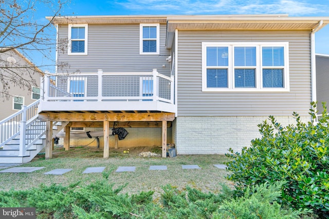 back of property featuring a wooden deck, a lawn, brick siding, and stairway