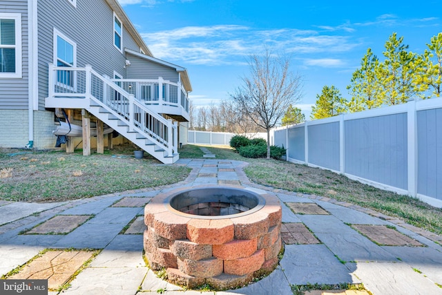 view of yard featuring stairway, a fenced backyard, a fire pit, a deck, and a patio area