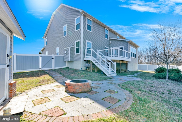 back of property with a gate, a fenced backyard, a fire pit, stairs, and a patio area