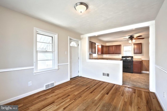 kitchen featuring visible vents, a peninsula, black range with electric stovetop, and wood finished floors