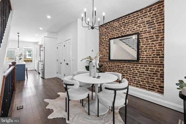 dining room with an accent wall, baseboards, dark wood-type flooring, and brick wall