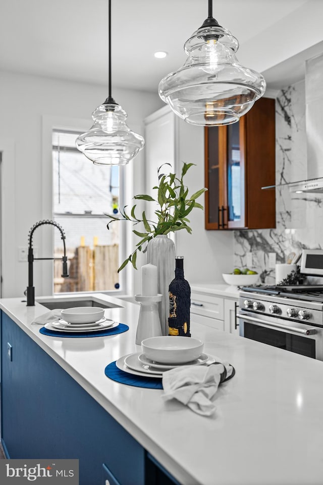 kitchen featuring tasteful backsplash, stainless steel range with gas cooktop, glass insert cabinets, and light countertops