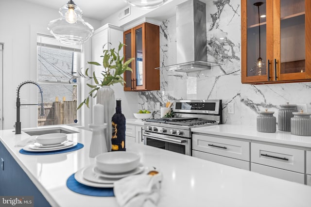 kitchen with light countertops, stainless steel range with gas stovetop, visible vents, and wall chimney exhaust hood