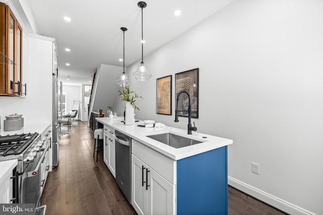 kitchen with an island with sink, dark wood-style flooring, stainless steel appliances, light countertops, and a sink