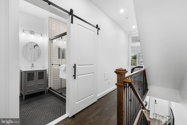 corridor with a barn door, recessed lighting, visible vents, an upstairs landing, and dark wood-style floors