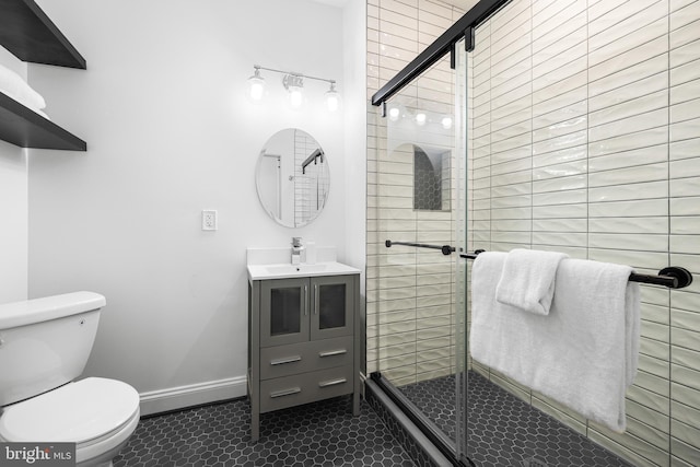 full bath featuring tile patterned flooring, toilet, vanity, baseboards, and a shower stall