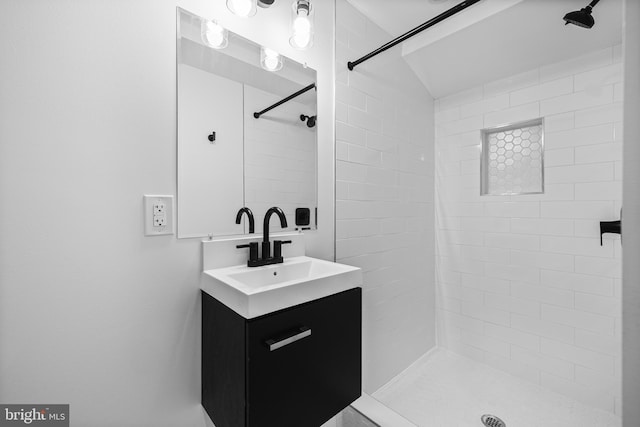 bathroom with tiled shower and vanity