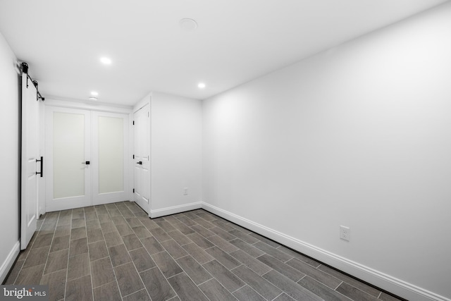 empty room with recessed lighting, dark wood-style flooring, baseboards, and a barn door