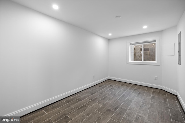 spare room with recessed lighting, dark wood-style flooring, electric panel, and baseboards