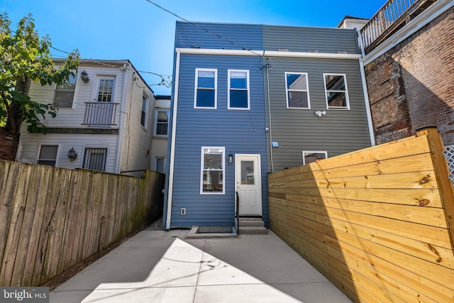 rear view of property featuring entry steps, fence, and a patio