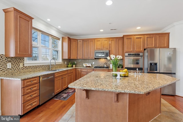 kitchen featuring a sink, light stone countertops, appliances with stainless steel finishes, and ornamental molding