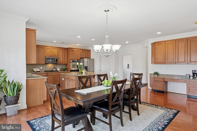 dining space with crown molding, a notable chandelier, light wood-style floors, and built in study area