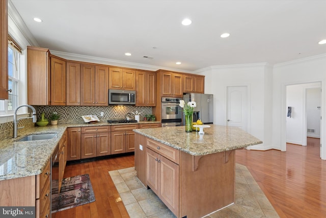 kitchen with a sink, decorative backsplash, ornamental molding, and stainless steel appliances