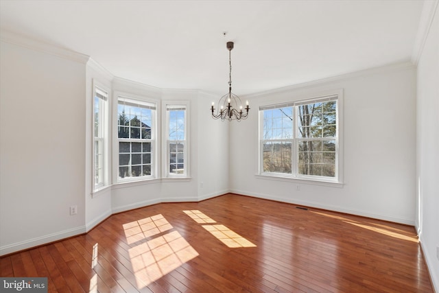 unfurnished dining area with baseboards, a notable chandelier, crown molding, and hardwood / wood-style flooring