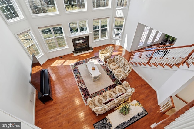 living area featuring a high end fireplace, stairway, a towering ceiling, and hardwood / wood-style floors