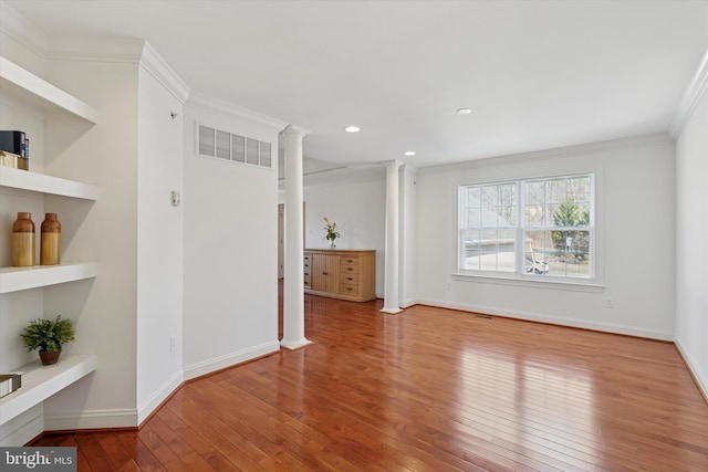 interior space with baseboards, visible vents, decorative columns, wood-type flooring, and crown molding