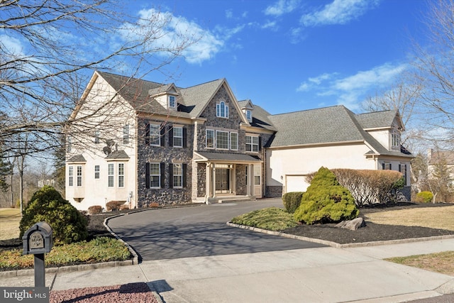 view of front of home featuring aphalt driveway, stone siding, and stucco siding