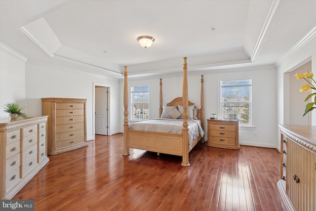 bedroom featuring light wood finished floors, crown molding, a raised ceiling, and baseboards