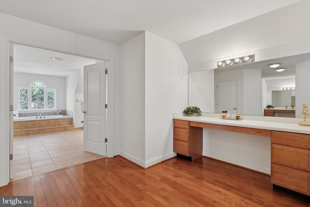 full bath with baseboards, vanity, a garden tub, and hardwood / wood-style flooring