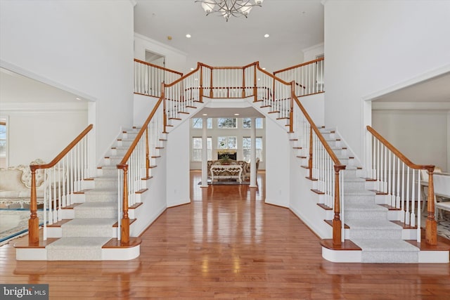 staircase featuring baseboards, a high ceiling, hardwood / wood-style floors, and crown molding