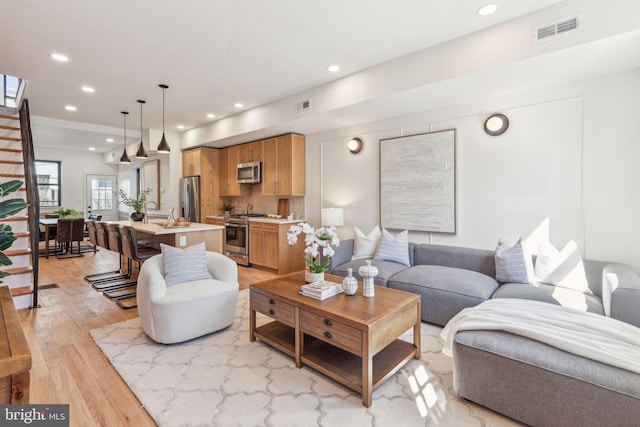 living room featuring stairway, light wood-style flooring, visible vents, and recessed lighting