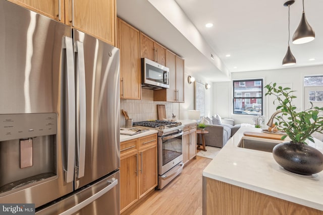 kitchen featuring appliances with stainless steel finishes, light countertops, a sink, and tasteful backsplash