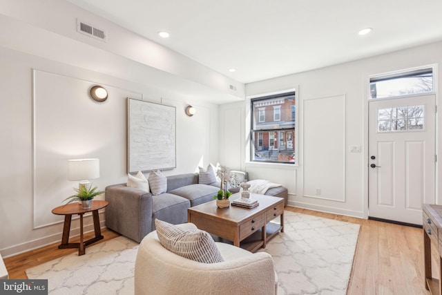 living area featuring visible vents, baseboards, light wood-style flooring, and recessed lighting