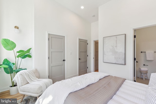 bedroom with a towering ceiling, baseboards, wood finished floors, and recessed lighting