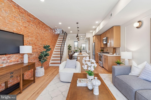 living area featuring recessed lighting, visible vents, stairway, light wood-style floors, and brick wall