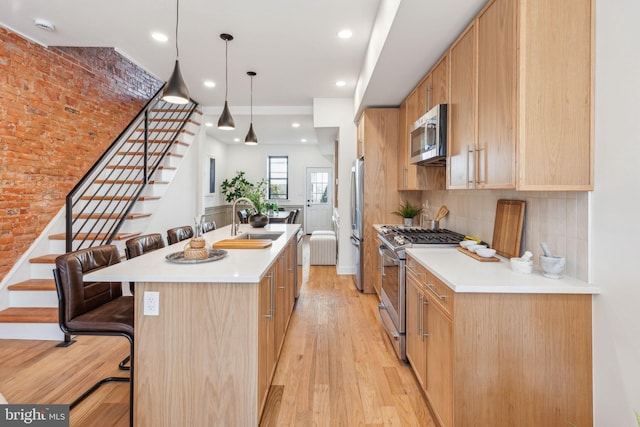 kitchen featuring light brown cabinets, light wood-style flooring, stainless steel appliances, a sink, and decorative backsplash