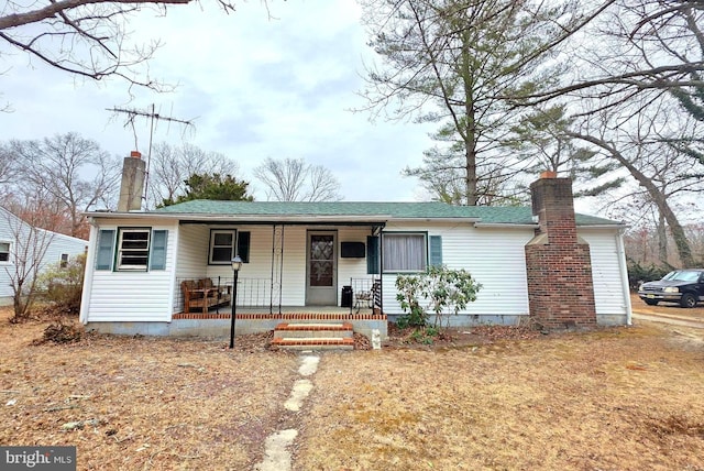 single story home featuring covered porch, a shingled roof, crawl space, and a chimney