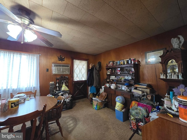 interior space with wood walls, a wall mounted AC, carpet, and a ceiling fan