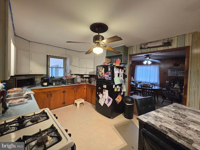 kitchen with a toaster, white range with gas cooktop, light countertops, freestanding refrigerator, and stainless steel microwave