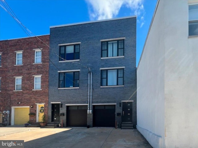 multi unit property featuring driveway, an attached garage, and brick siding