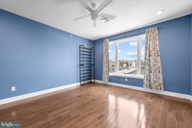 spare room with ceiling fan, wood finished floors, visible vents, and baseboards