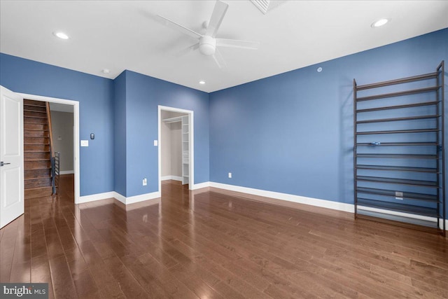 unfurnished bedroom with recessed lighting, wood finished floors, a walk in closet, and baseboards