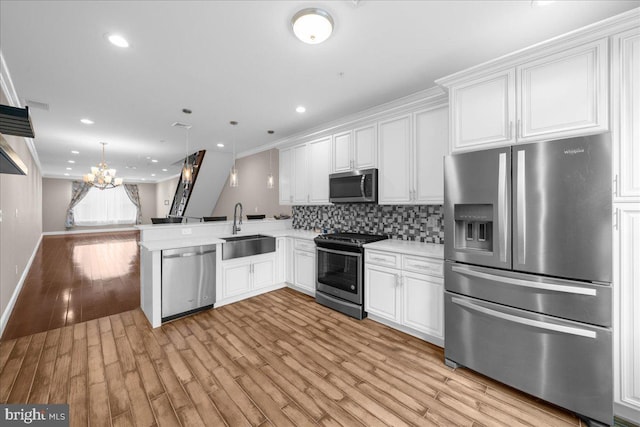 kitchen with light countertops, decorative backsplash, appliances with stainless steel finishes, white cabinetry, and a sink