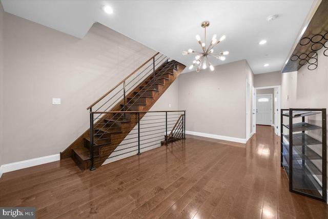 stairs with a notable chandelier, recessed lighting, wood finished floors, and baseboards