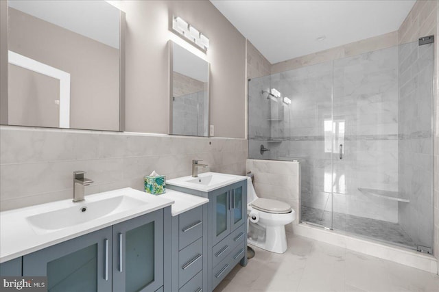 bathroom with a stall shower, toilet, a sink, marble finish floor, and tile walls