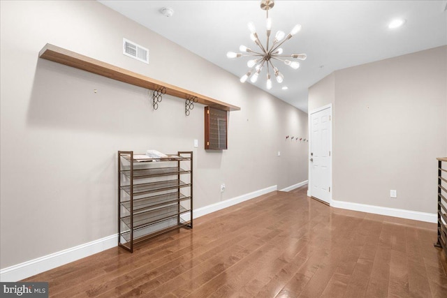 basement with an inviting chandelier, visible vents, baseboards, and wood finished floors