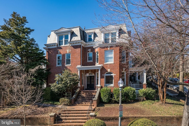 second empire-style home featuring brick siding, mansard roof, and a high end roof