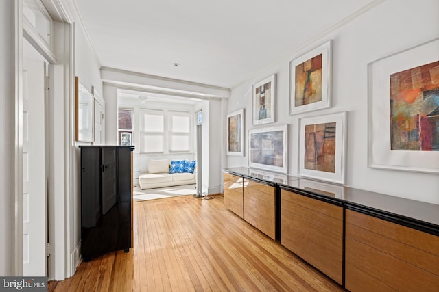 hall with light wood finished floors and crown molding