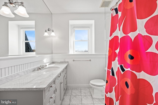 bathroom featuring a wainscoted wall, visible vents, plenty of natural light, and marble finish floor