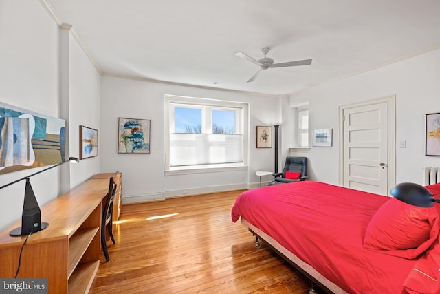 bedroom with radiator, ornamental molding, ceiling fan, baseboards, and hardwood / wood-style flooring