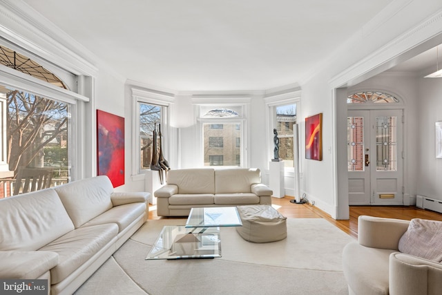 living area featuring a baseboard radiator, crown molding, baseboards, and wood finished floors