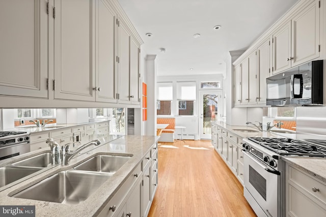 kitchen with range with gas stovetop, light wood finished floors, a baseboard radiator, a sink, and black microwave