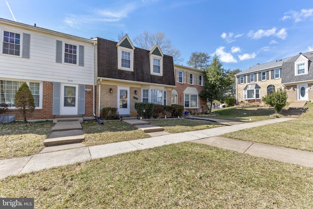 view of front of house with a shingled roof, a front yard, a residential view, and brick siding